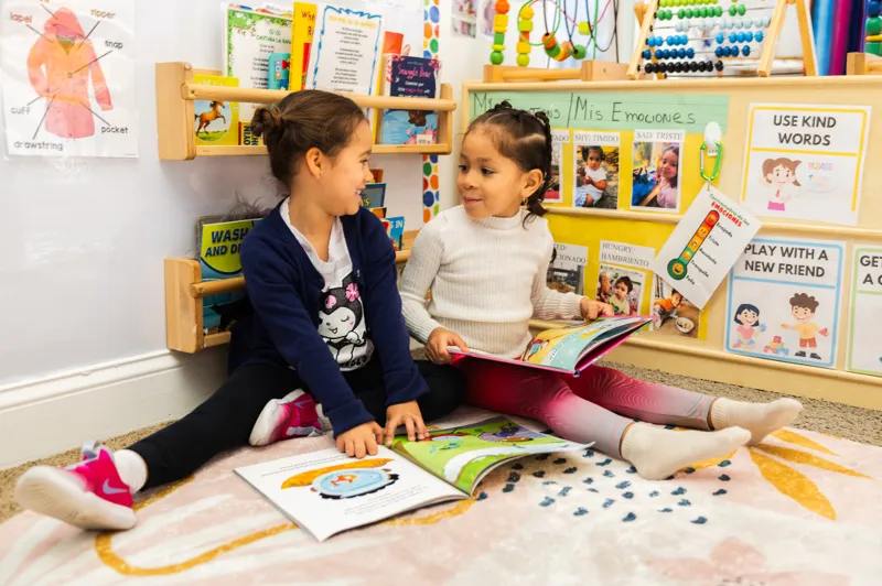 Dos niños pequeños sentados uno frente al otro durante una actividad en el aula.