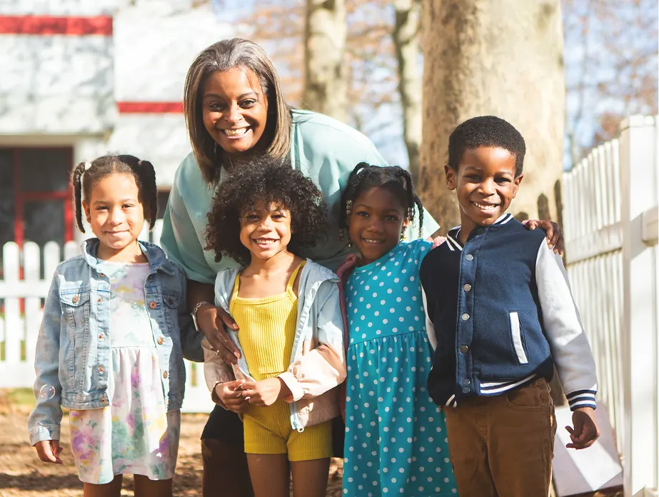 Group of young children standing outside with an adult.